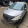 Frente de um Peugeot 207 Passion cinza estacionado em pátio automotivo.
