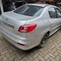 Traseira de um Peugeot 207 Passion cinza estacionado em pátio automotivo.