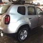 Renault Duster prata estacionado em pátio automotivo.