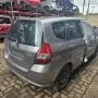 Fit cinza estacionado em pátio automotivo.
