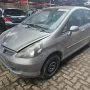 Fit cinza estacionado em pátio automotivo.