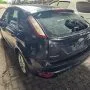 Ford Focus preto estacionado em pátio automotivo.