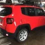 Jeep Renegade vermelho estacionado em pátio automotivo.