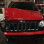 Frente de um Jeep Renegade vermelho estacionado em pátio automotivo.