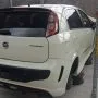Traseira de um Punto branco estacionado em pátio automotivo.