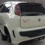 Traseira de um Punto branco estacionado em pátio automotivo.