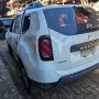 Renault Duster branco estacionado em pátio automotivo.