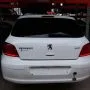 Traseira de um Peugeot 307 branco estacionado em pátio automotivo.